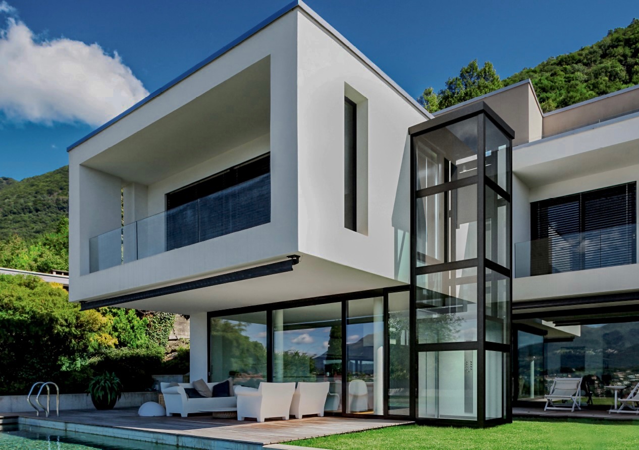 Glass-enclosed LussoLift home elevator on a modern villa exterior with pool
