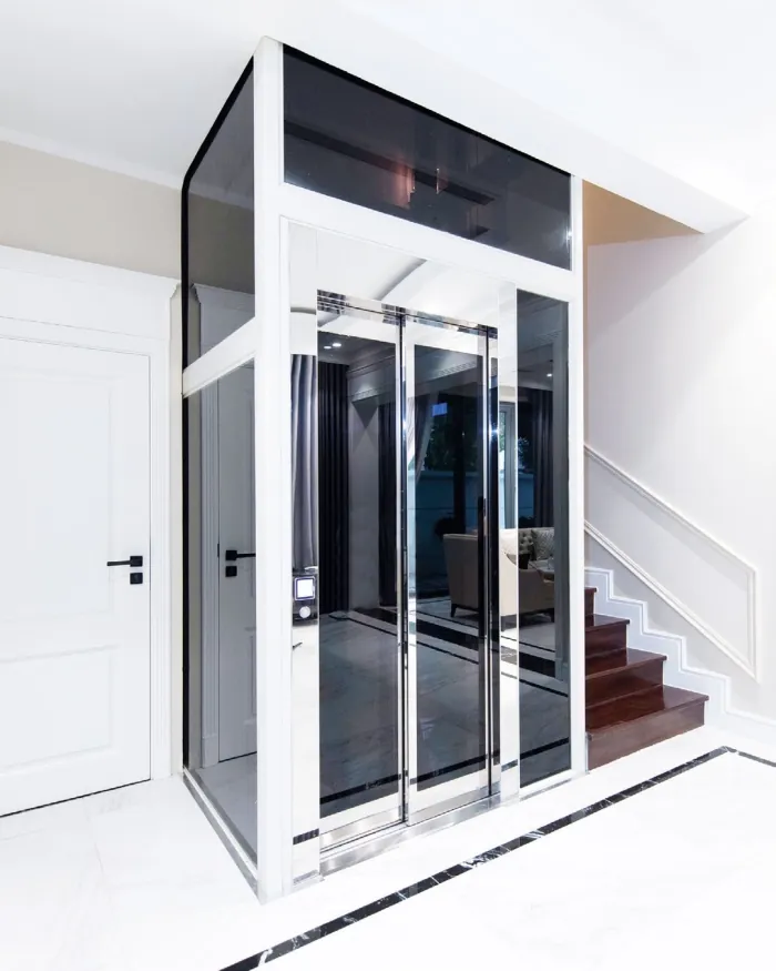 Representative installation: a white-framed glass elevator in a bright hall beside the stairs.
