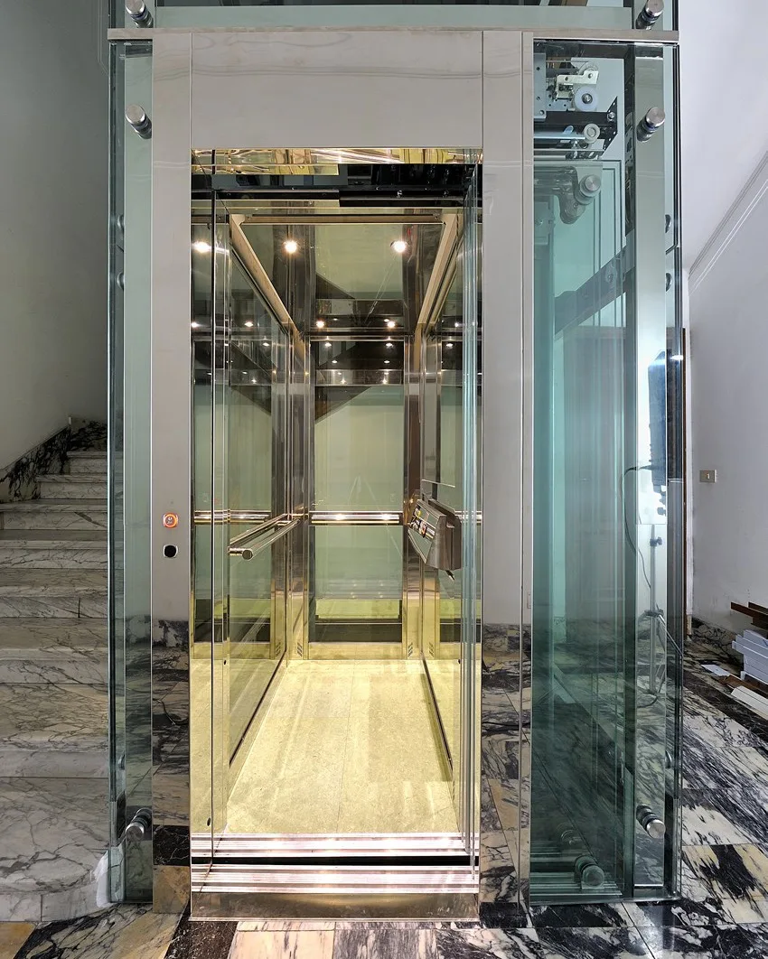 Representative installation: the panoramic glass cab of a traction elevator, with warm lighting.