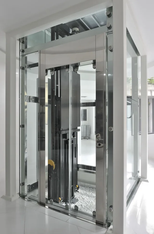 Glass elevator structure showing the traction machinery, in a white room