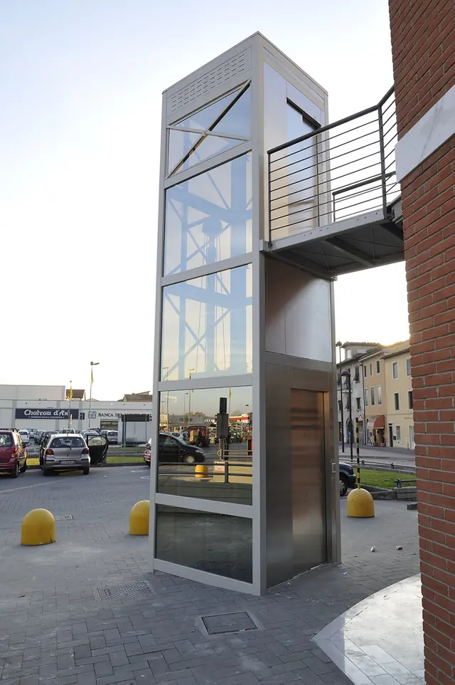 Outdoor glass elevator structure with a walkway to the upper floor