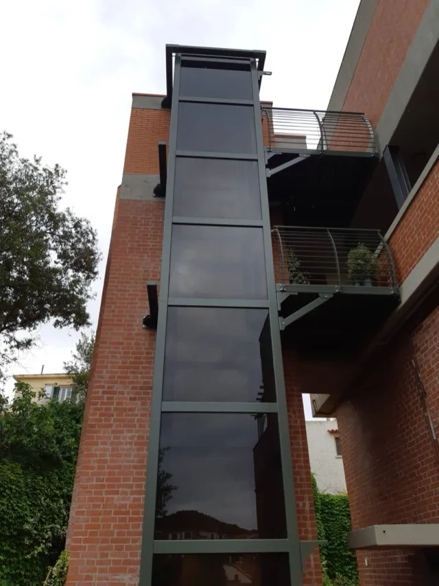 Smoked glass elevator structure on the outside of a brick house