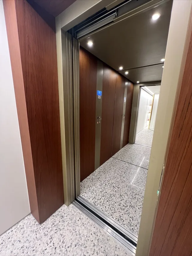 Elevator cab in walnut panels with a terrazzo floor